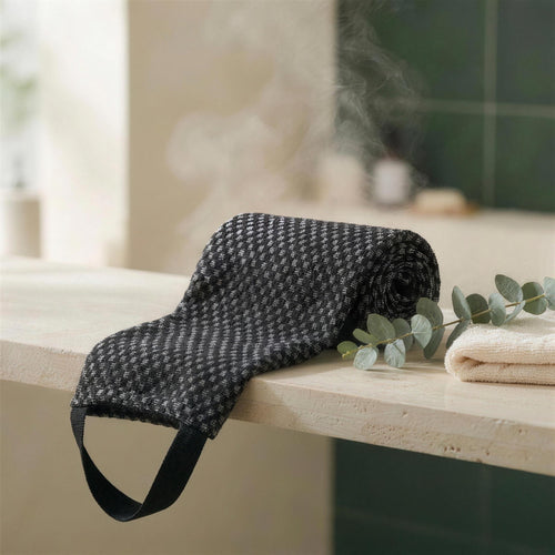 Serviette exfoliante Seshin noire posée sur un rebord en pierre, salle de bain vapeur