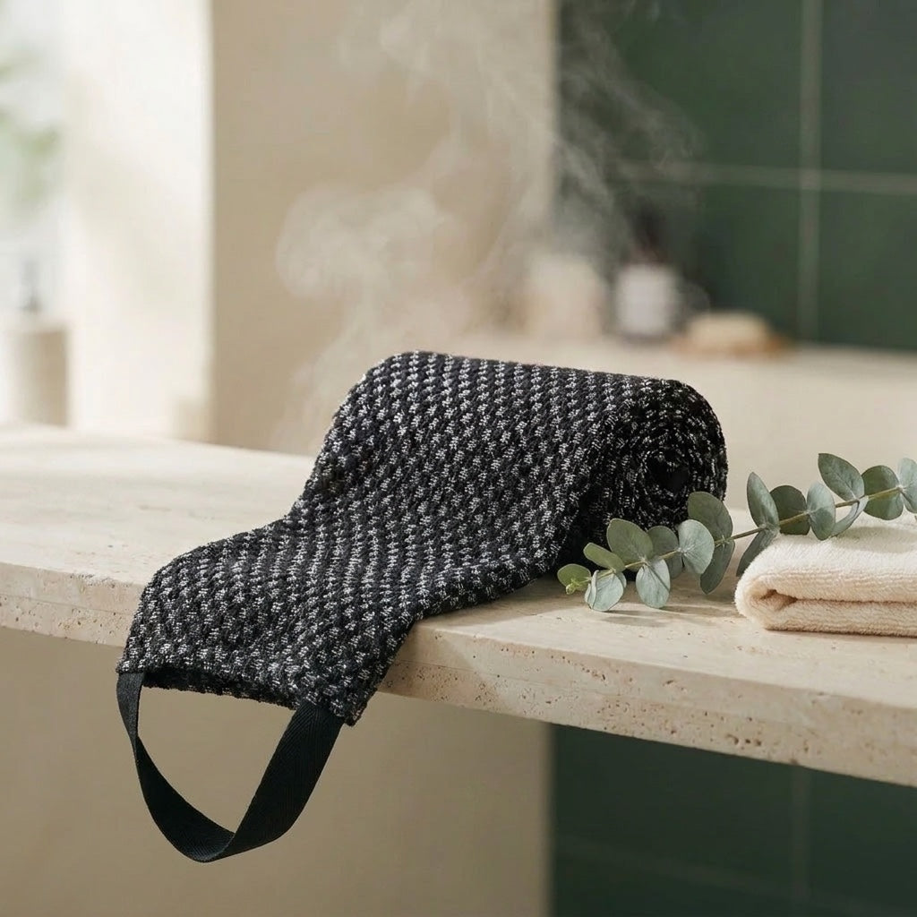 La serviette Seshin noire posée sur pierre travertin, vapeur et eucalyptus